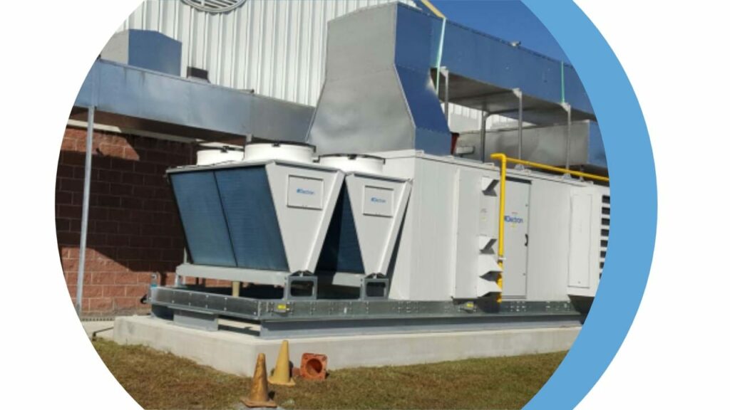 A Dectron rooftop dehumidification unit on a concrete pad outside a metal building, ductwork rising over the roof behind it