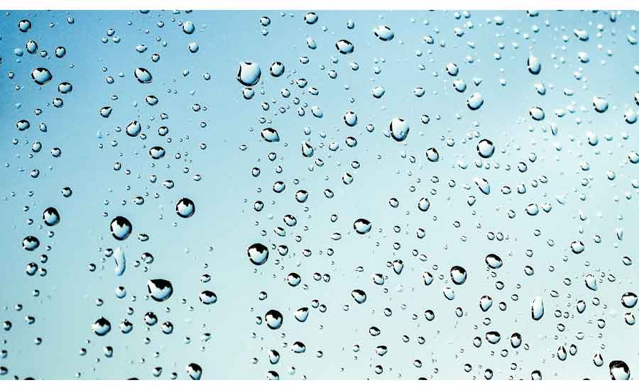 Water droplets across a pane of glass against a pale blue background