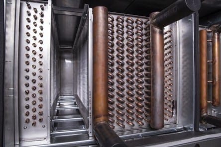 Inside an air handling unit, the copper coil banks of a wrap-around heat exchanger either side of the airway