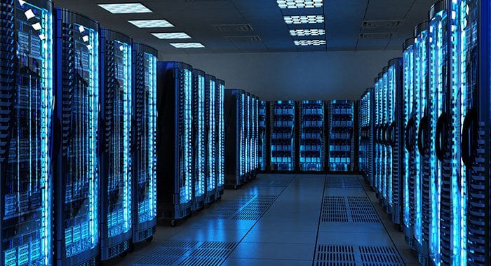 An aisle between two walls of blue-lit server racks, more rows visible at the far end