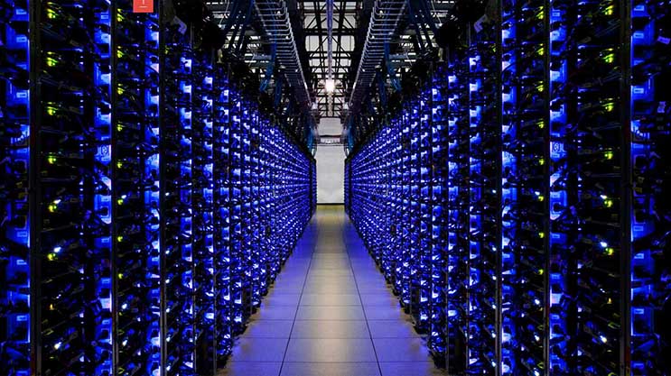 A long aisle between two walls of densely packed, blue-lit server racks