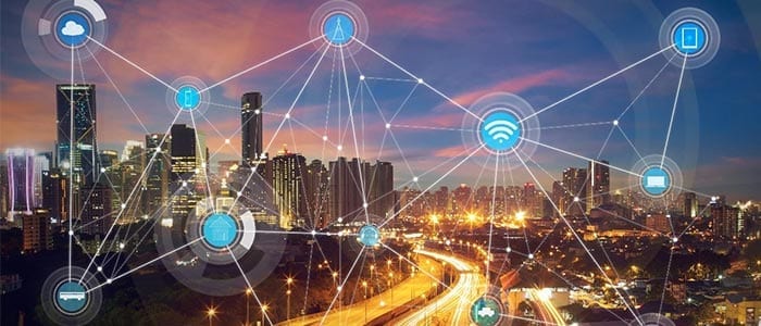 A city at dusk overlaid with a web of connected device icons