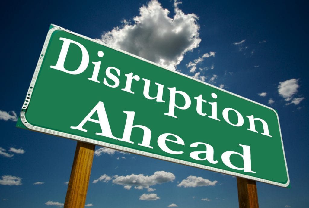 A green highway sign reading "Disruption Ahead" against a blue sky