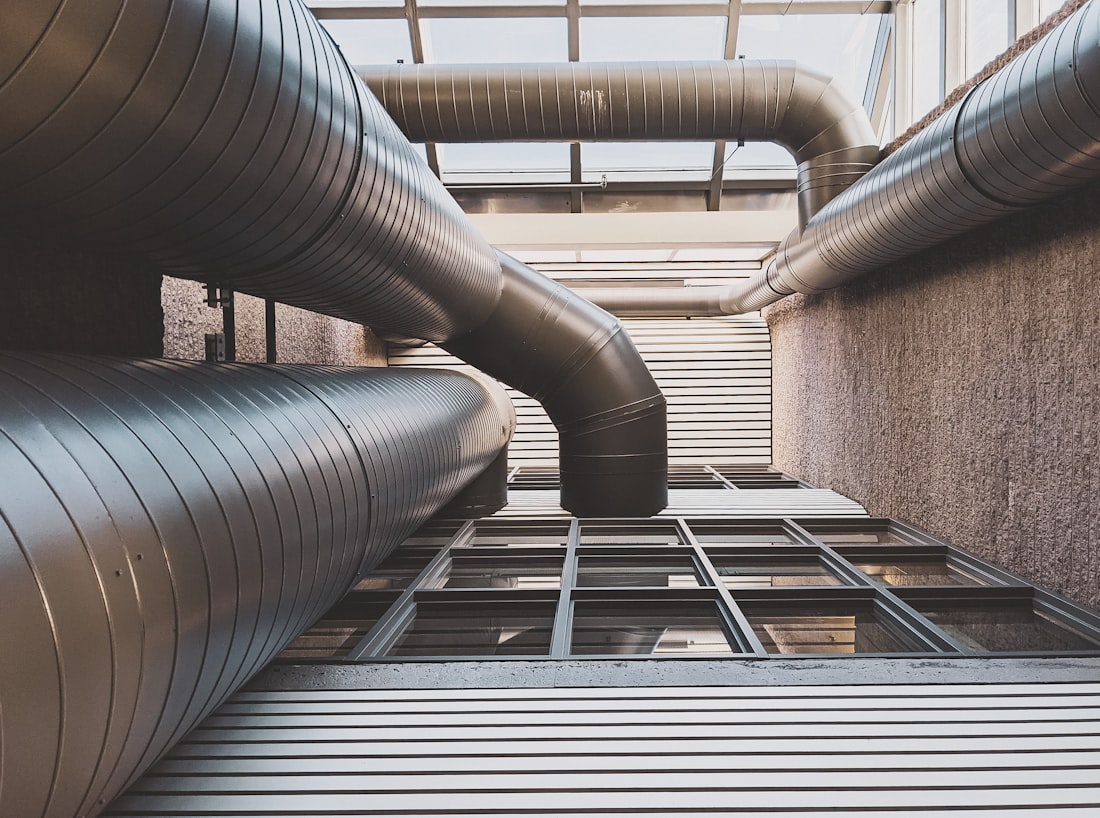 Large insulated sheet-metal air ducts running along the walls of a building light well, seen from below