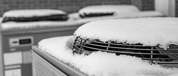 Outdoor condensing units under a covering of snow, the fan grille of the nearest one half buried